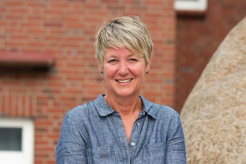 Portraitfoto von der Bürgermeisterin Uta Bielfeldt vor einer roten Steinmauer