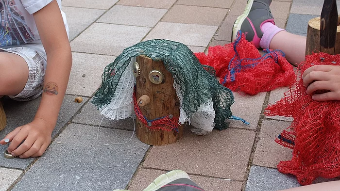 Kinder sitzen auf dem Boden vor dem Rathaus und Basteln