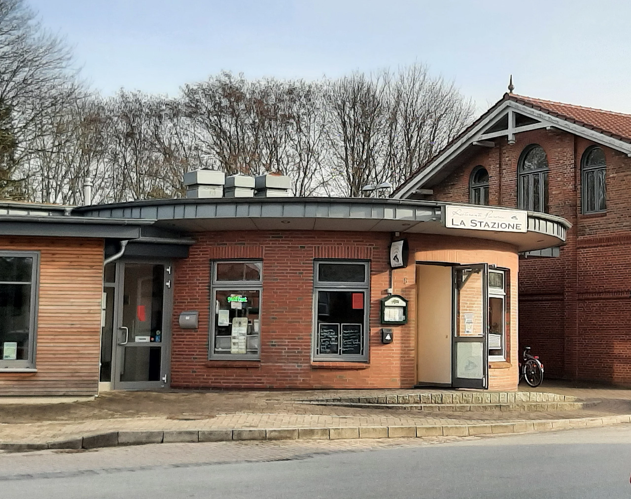 Es ist ein runder Backsteinbau direkt am Meldorfer Bahnhof. Im Hintergrund sind hohe Bäume zu sehen.